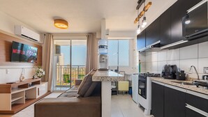 A modern kitchen with a built-in oven, a coffee machine, and a sink. There is a TV mounted on the wall displaying a Netflix show. - Mirante #1404 - Fortaleza by Carpediem (Fortaleza)