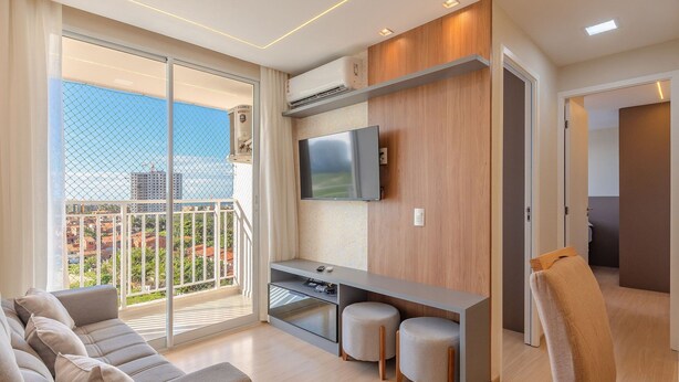 Ein modernes Wohnzimmer mit Sofa, Fernseher und Balkon mit Blick auf die Stadt.