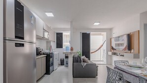 A modern kitchen with a refrigerator, stove, and microwave. There is a dining area with a table and chairs. - Mirante #807 - Praia do Futuro by Carpediem (Fortaleza)