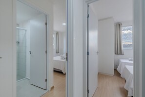 A hotel room with a shower, a bed, a bedside table, and a window with curtains. - Mirante #607 - Apartment in Fortaleza by Carpediem (Fortaleza)