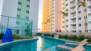 A swimming pool with lounge chairs, surrounded by high-rise buildings. - Mirante Clube #606 - Apto 2 Quartos by Carpediem (Fortaleza)