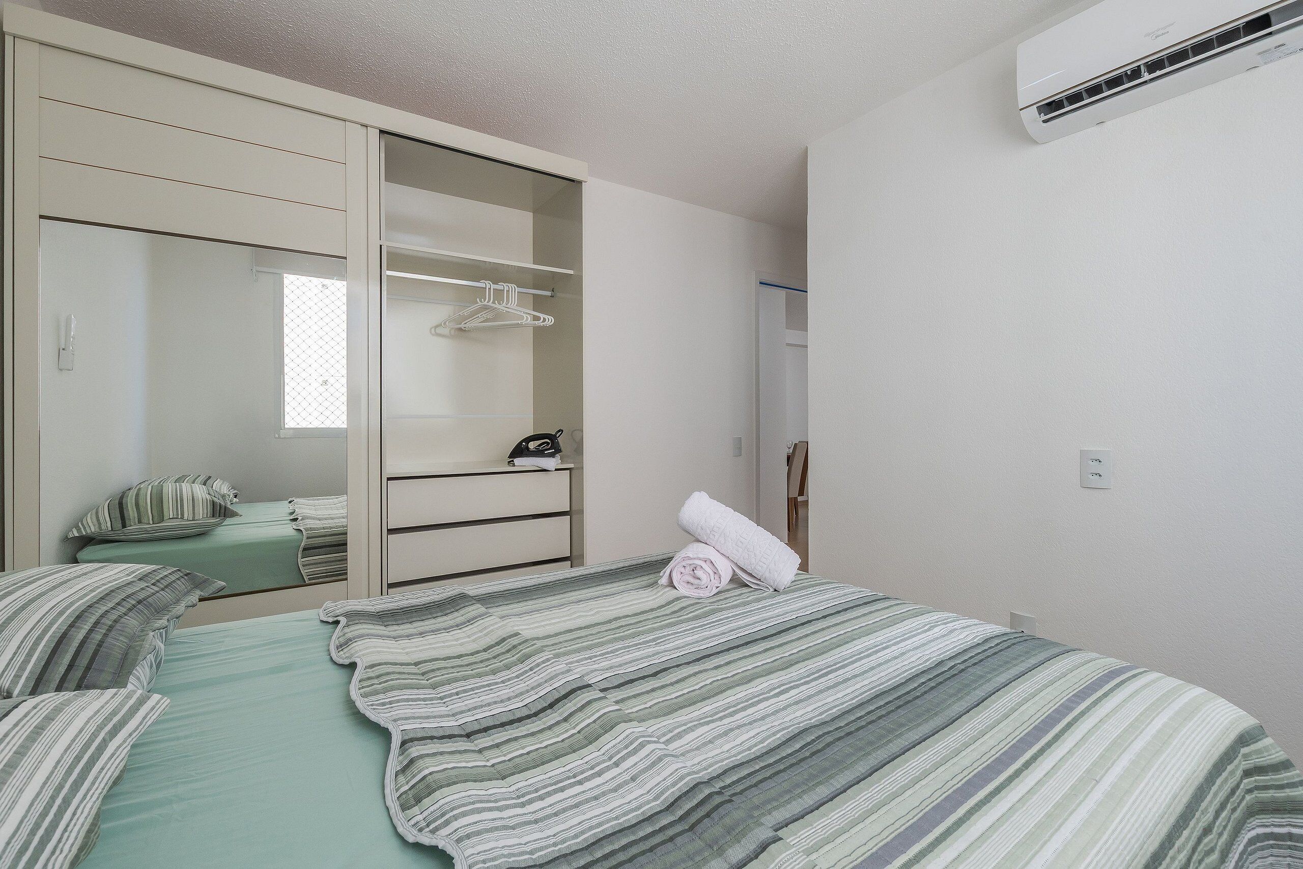 Un dormitorio con cama, armario y espejo.