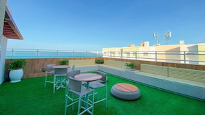 A rooftop terrace with green artificial grass, seating areas, and a view of the sea. - Mirante #407 - Two-bedroom Apt By Carpediem (Fortaleza)
