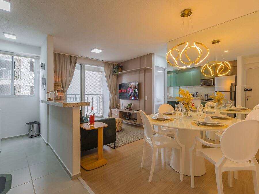A modern living room with a dining area, a kitchen, and a balcony.