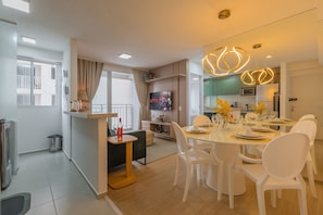 A modern living room with a dining area, a kitchen, and a balcony. - Mirante #307 - Space and Style by Carpediem (Fortaleza)