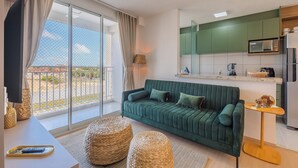 A modern living room with a green sofa, a flat-screen TV, and a balcony with a view. - Mirante #307 - Space and Style by Carpediem (Fortaleza)