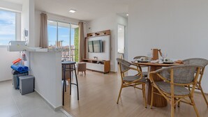 A modern kitchen with a built-in oven, a dining area with wicker chairs, and a large window offering a view of the outdoors. - Mirante #303 2 Suites Praia Futuro by Carpediem (Fortaleza)