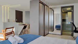 A modern hotel room with a bed, a desk, a chair, and a sliding door leading to a bathroom. - Iate Plaza #1404 - Studio Vista Mar por Carpediem (Fortaleza)