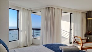 A hotel room with a large bed, a chair, and a view of the sea through a window. - Iate Plaza #1404 - Studio Vista Mar por Carpediem (Fortaleza)