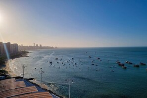 A coastal cityscape with a marina filled with boats, a beach, and high-rise buildings in the background. - Iate Plaza #1404 - Studio Vista Mar por Carpediem (Fortaleza)