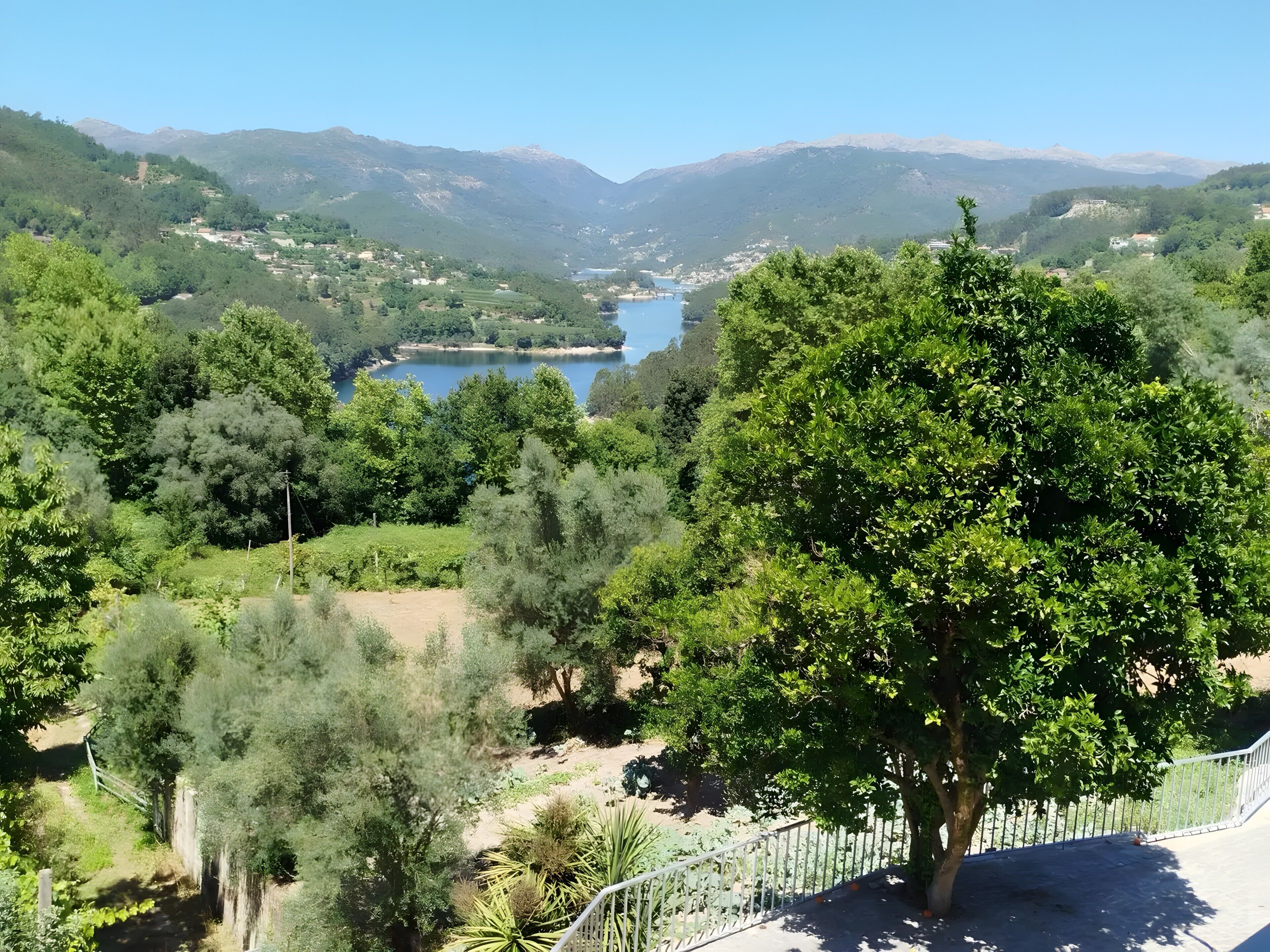 Paisatge de muntanyes amb un llac, arbres i un cel serè.
