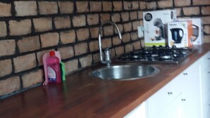 Ett kök med en tegelvägg, en diskho i rostfritt stål och en bänkskiva i trä.