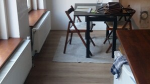 Ett smalt kök med ett matbord och stolar, ett element och en tegelvägg.