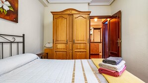 Ein Schlafzimmer mit einem Bett, einem Holzschrank und einem durch eine offene Tür einsehbaren Badezimmer.