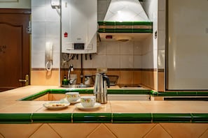 Una cocina con salpicadero de azulejos, una cafetera y un lavamanos.