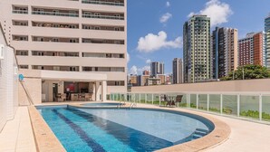 A swimming pool with a curved design, surrounded by a building with multiple floors and balconies. - Hiperion #502 - Apt in Fortaleza by Carpediem (Fortaleza)