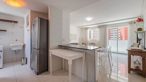 A compact kitchen with a refrigerator, sink, and a small dining area with chairs. - Hiperion #502 - Apt in Fortaleza by Carpediem (Fortaleza)