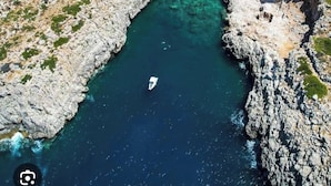 Un'area costiera con terreno roccioso e un mare cristallino.