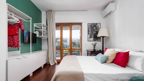 Un dormitorio con cama, armario, escritorio, ventana con vistas y aire acondicionado.