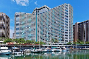 A marina with several boats docked, surrounded by high-rise buildings with balconies. - Iconic Ilikai 16th-FL Ocean & Harbor View Suite, Full Kitchen & Private Lanai (Honolulu)