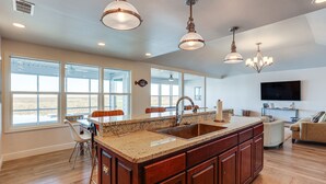 A spacious kitchen with a large island, wooden cabinets, and a modern chandelier. - Waterfront NOLA Gem w/ Boat Dock & Lift on Wildlife Refuge (New Orleans)