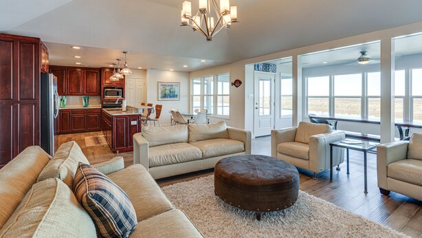 A spacious living room with a large sofa, ottoman, and a dining area with a table and chairs. - Waterfront NOLA Gem w/ Boat Dock & Lift on Wildlife Refuge (New Orleans)