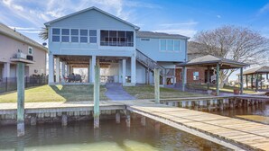 A waterfront property with a covered patio, a dock, and a building with a large window and a covered entryway. - Waterfront NOLA Gem w/ Boat Dock & Lift on Wildlife Refuge (New Orleans)