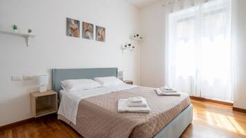 Une chambre bien rangée, avec un lit, des tables de chevet et des étagères murales ornées de plantes.