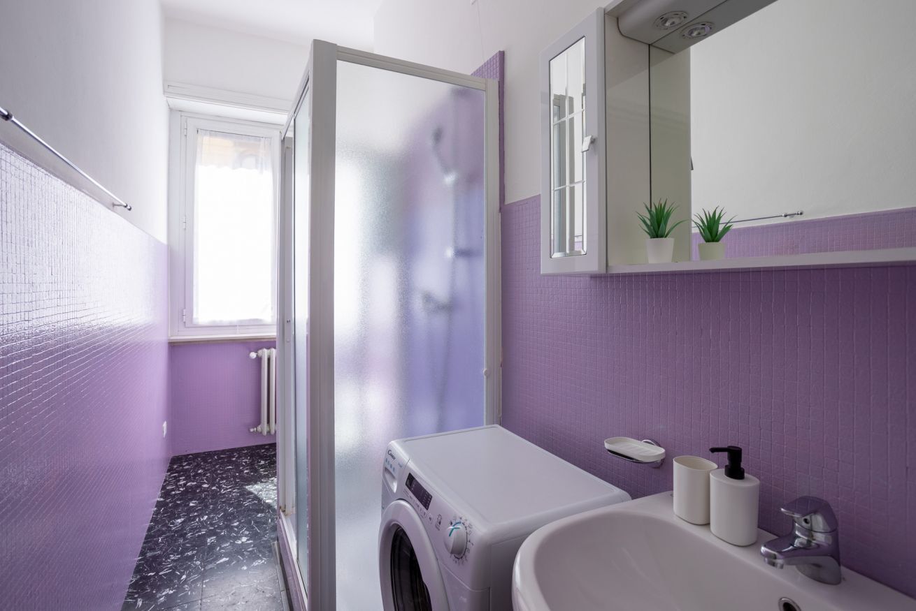 Une salle de bain équipée d’un lave-linge, d’un lavabo et d’un miroir.