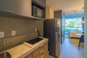 Eine moderne Küche mit integriertem Mikrowellenherd, einem Edelstahlkühlschrank, einer Granit-Arbeitsplatte und Blick auf den Balkon.