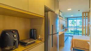 A compact kitchen with a coffee maker, a refrigerator, and a bed in the adjacent room. - Beach Class Summer #303 Ipojuca By Carpediem (Ipojuca)