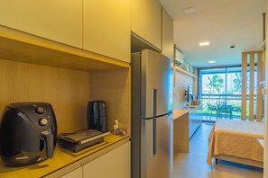 A compact kitchen with a coffee maker, a refrigerator, and a bed in the adjacent room. - Beach Class Summer #303 Ipojuca By Carpediem (Ipojuca)