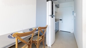 A compact kitchen with a white refrigerator, a dining table with two chairs, and a small countertop. - Beach Class Summer #d311 - Ape por Carpediem (Ipojuca)