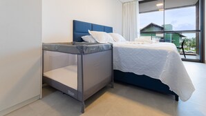 A modern bedroom with a bed, a small bench, and a large window with a view of buildings. - Beach Class Summer #d311 - Ape por Carpediem (Ipojuca)