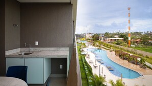 A balcony with a kitchen area, a swimming pool, and a view of the surrounding landscape. - Beach Class Summer #d311 - Ape por Carpediem (Ipojuca)