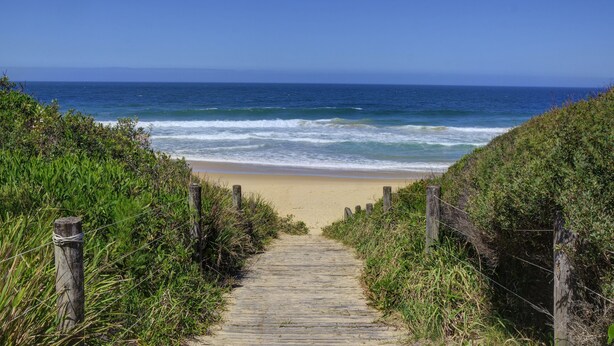 A wooden pathway leading to a beach with ocean views. - Diamond Beach Beachfront Family Apt (Diamond beach)