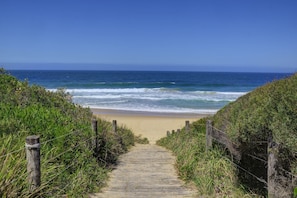 Un sendero de madera que lleva a una playa con vistas al océano.