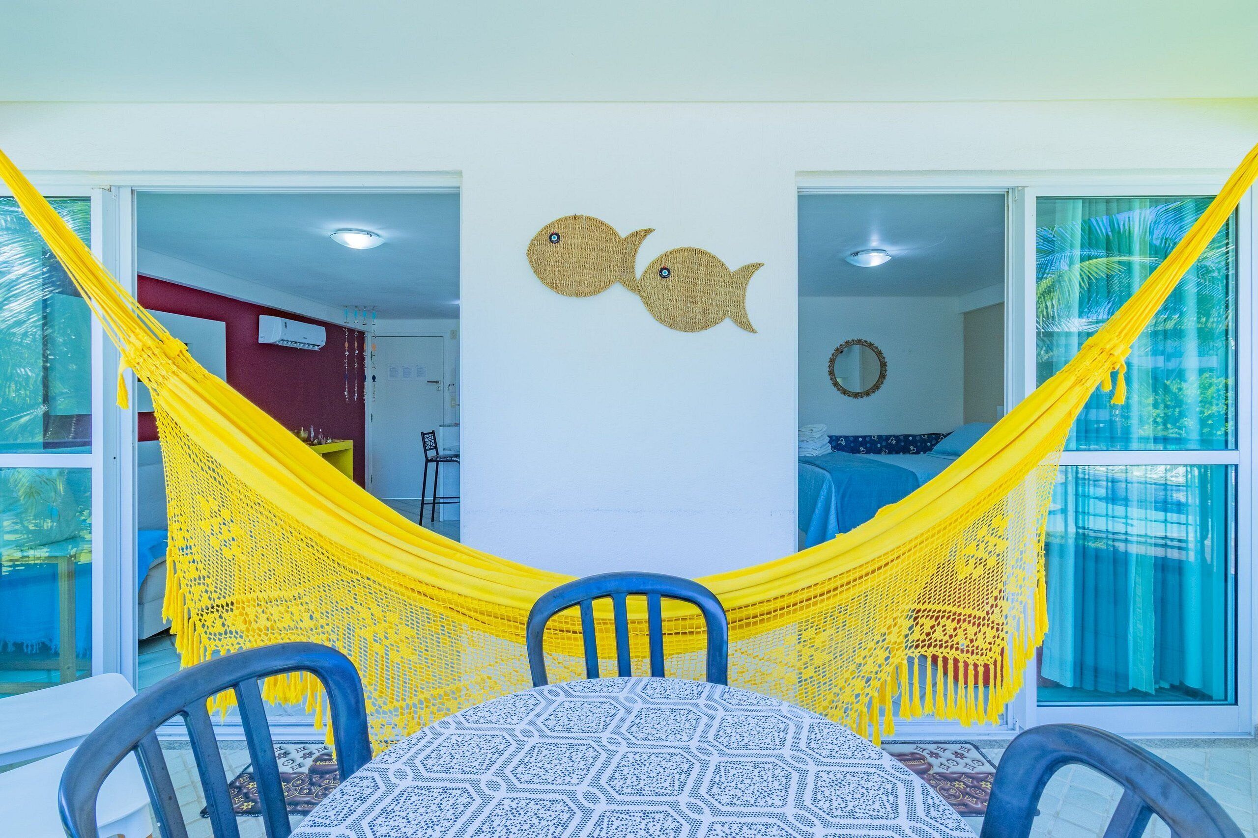 A dining area with a table and chairs, a yellow hammock, and two wall decorations.