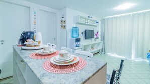A modern kitchen with a marble countertop, a water dispenser, and a television on a shelf. - Ancorar Resort #3103 - Beira Mar by Carpediem (Ipojuca)