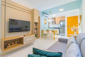 A modern living room with a flat-screen TV, a sofa, and a dining area with chairs and a table. - Mana Beach #d322 - Two Bedrooms by Carpediem (Ipojuca)