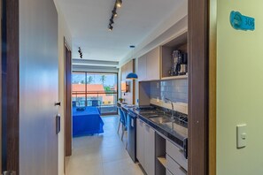 A modern kitchen with a built-in stove, a sink, and a blue pendant light. - Ora Beach #306 - Studio With Balcony by Carpediem (Ipojuca)
