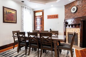 Ein Essbereich mit Holztisch und Stühlen, einem Kamin, einer Uhr und einem 'BISTRO'-Schild an der Wand.