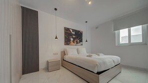 Una camera da letto moderna con un letto grande, comodini, un'opera d'arte appesa al muro e una finestra che offre luce naturale.