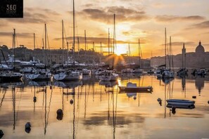 A marina with multiple boats docked at sunset. - Central Gzira 2BR Apartment | Balcony & Comfort (Gżira)