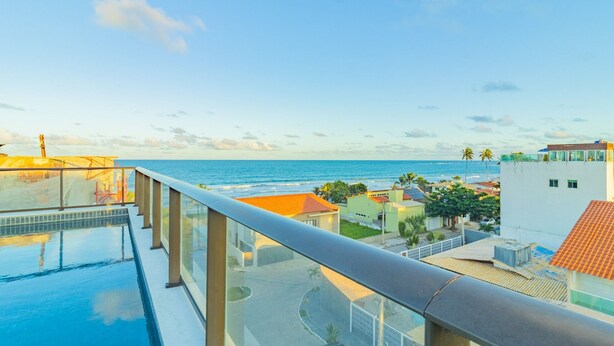 A rooftop infinity pool with a view of the ocean and surrounding buildings. - Ora Beach #315 - Porto de Galinhas by Carpediem (Ipojuca)