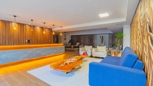 A modern lobby with a reception desk, seating area, and decorative elements. - Ora Beach #315 - Porto de Galinhas by Carpediem (Ipojuca)