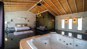 A spacious room with a large bathtub, a bed, and a sofa. - Villa Toprak (Kaş)