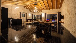 A spacious room with a pool table, a dining table with chairs, and a kitchen area with a washing machine. - Villa Toprak (Kaş)