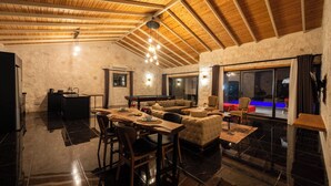 A spacious living area with a high wooden ceiling, a pool table, a sofa, and a dining table with chairs. - Villa Toprak (Kaş)