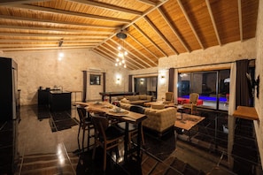 A spacious living area with a high wooden ceiling, a pool table, a sofa, and a dining table with chairs. - Villa Toprak (Kaş)